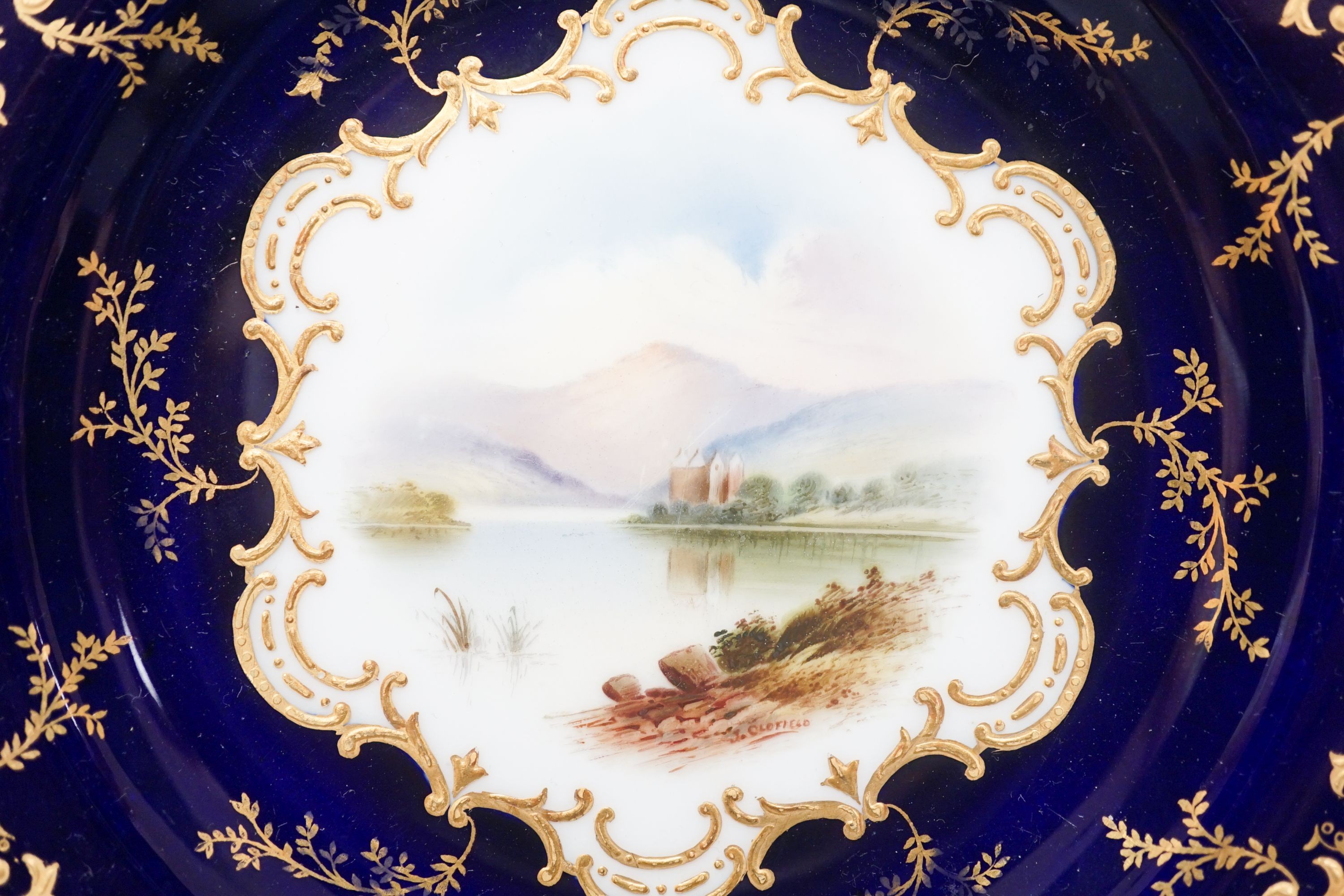 A pair of Coalport landscape plates painted by J. Oldfield with loch scenes, impressed date code for 1909, diameter 23cm